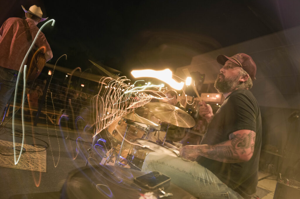 Live music at local roots in Vista, photo of a drummer with light effects coming from the cymbals.