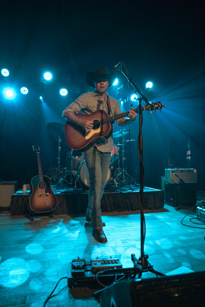 man playing guitar with blue lights behind him
