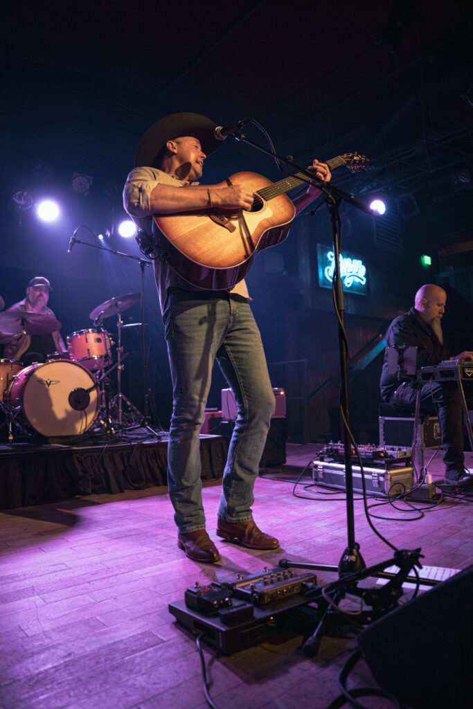 guitar player center stage with his guitar raised playing a finishing note
