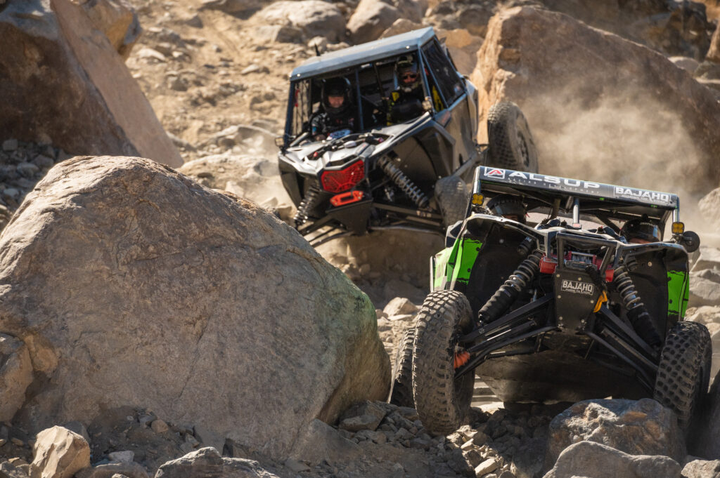 2 Can Am race cars crawling over rocks competing at The King of The Hammer off-road race. Photo by Rob Wessels  