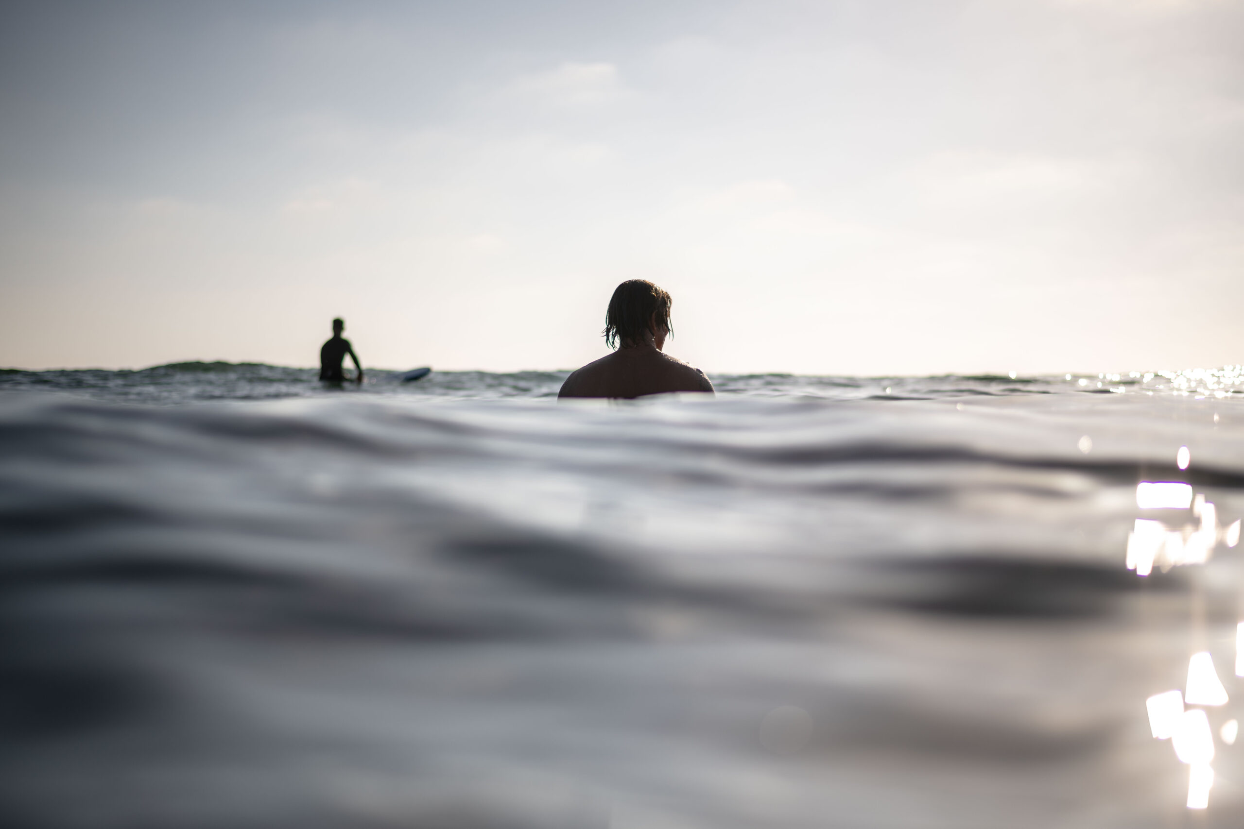 surfer sitting in the line up in Encinitas, One surfer in focus in the center of frame one out of focus in the left upper 3rd. photo was taken with a NIkon camera and Aquatech waterproof housing.