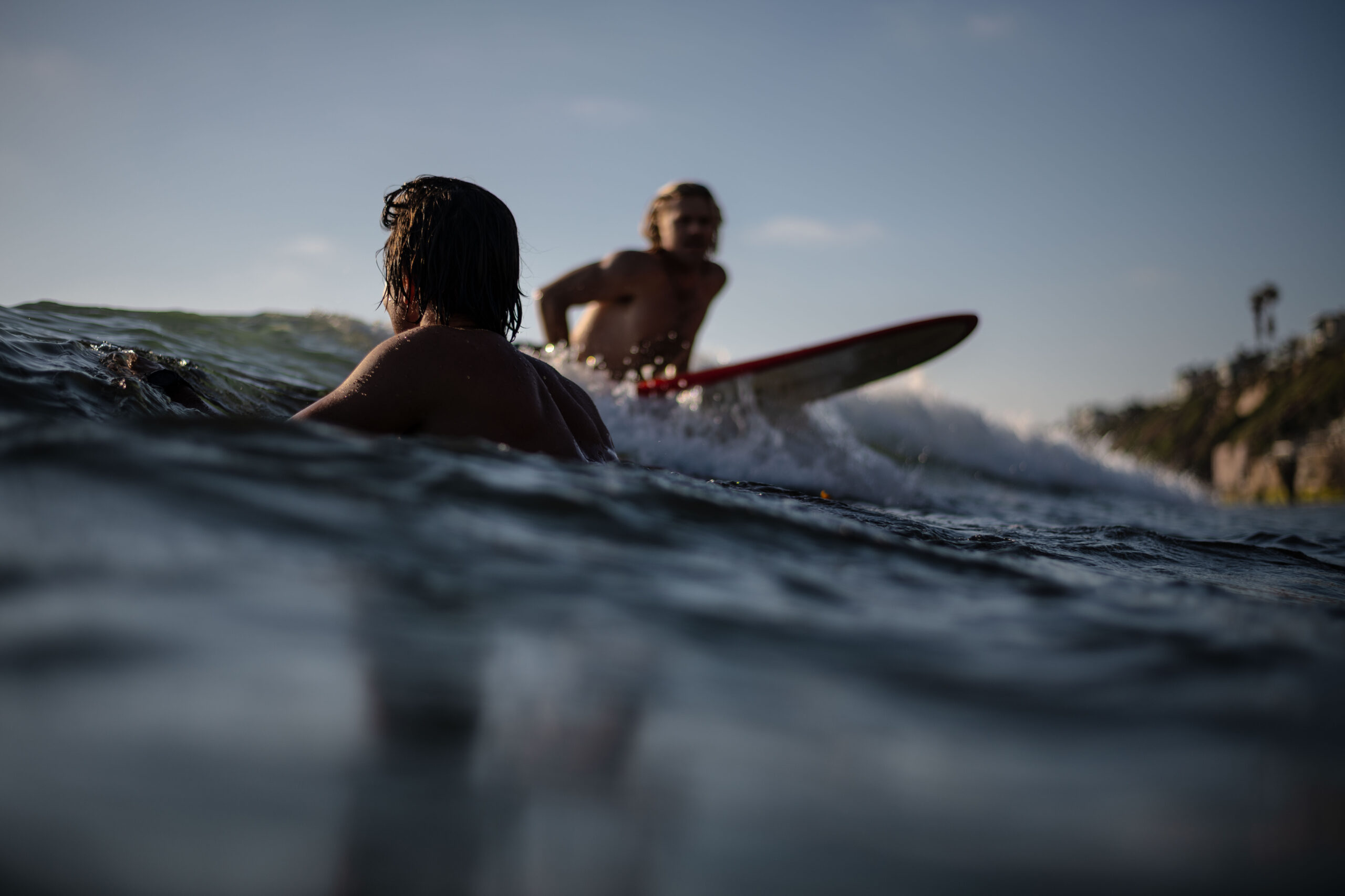 two surfers in the water at Beacons Beach in Encinitas. One paddling out and one trying to catch a wave.