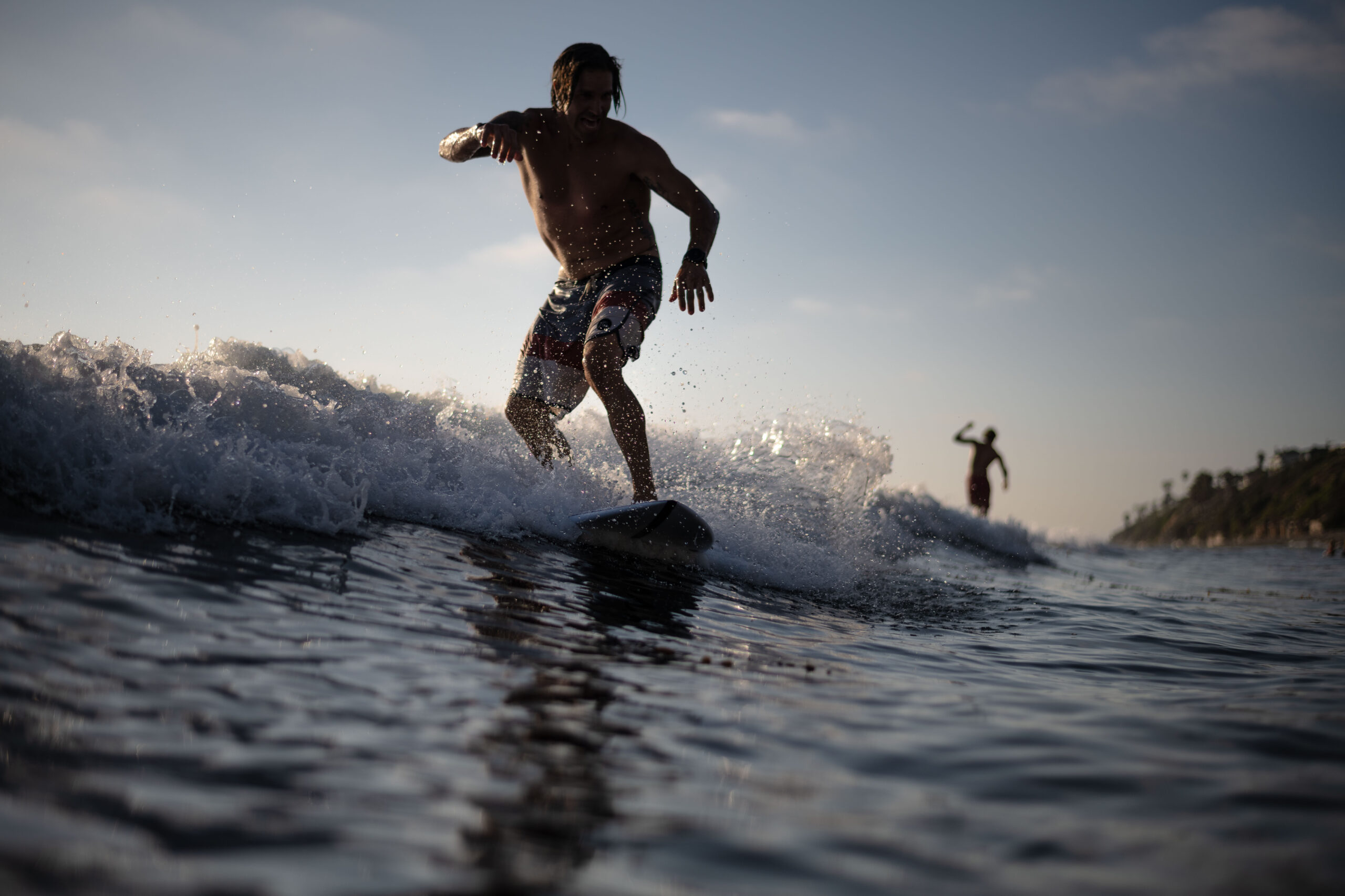 Surfer riding a wave with another surf silhouetted in the background at Beacons beach in Encinitas. Its a water angle shoot of the surfer shot with my Nikon D850 and Aquatech waterproof housing.