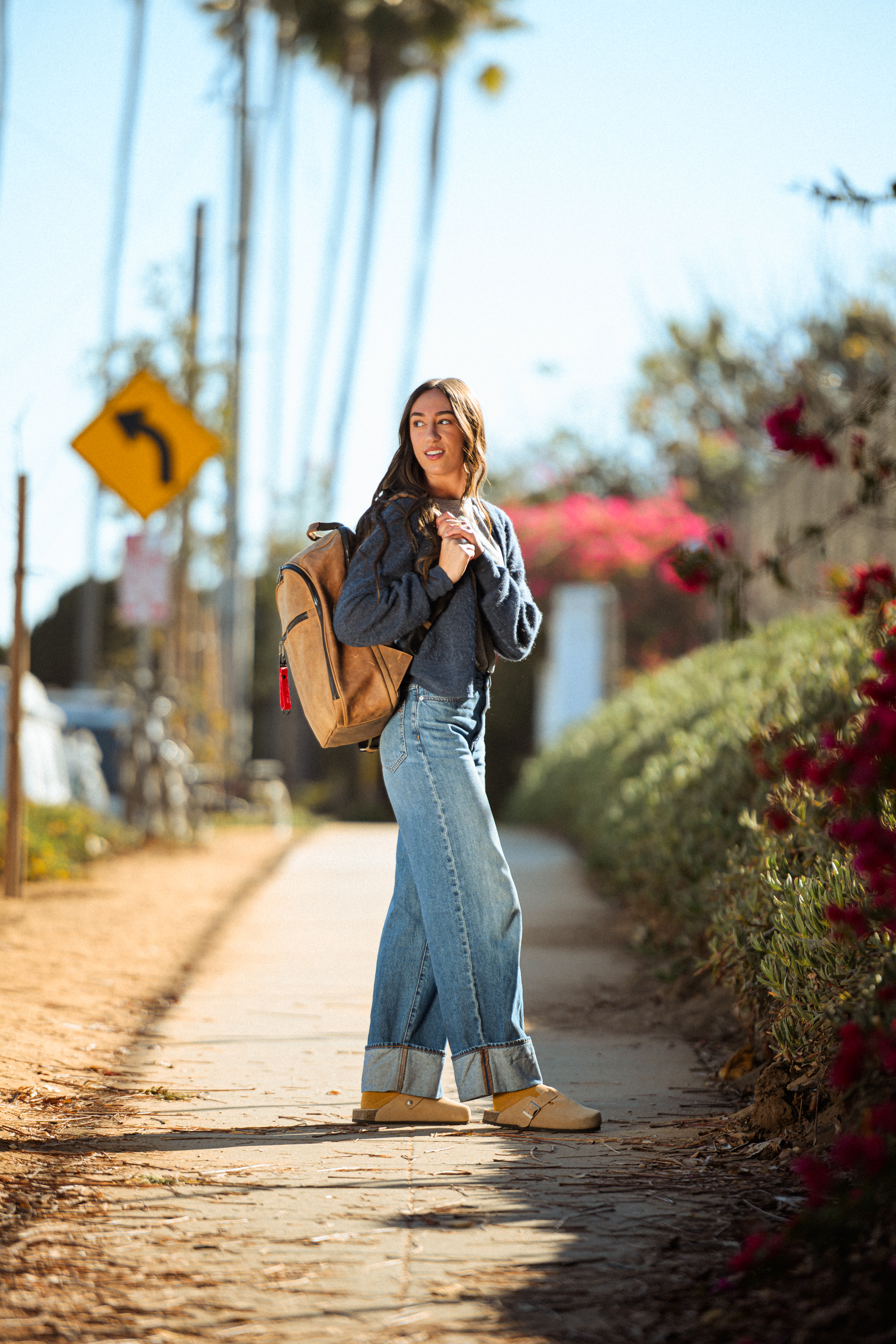 commercial fashion photography with rdub creative taking photos near swamis beach in ecinitas for a desinger handbag company, with a girl holding a backpack over her shoulder